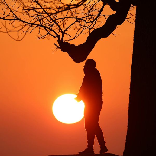 A silhouette of a man stretching against a warm, glowing background.